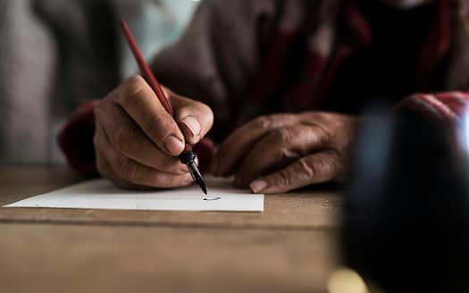 A man with dirty hands writing on a sheet of paper
